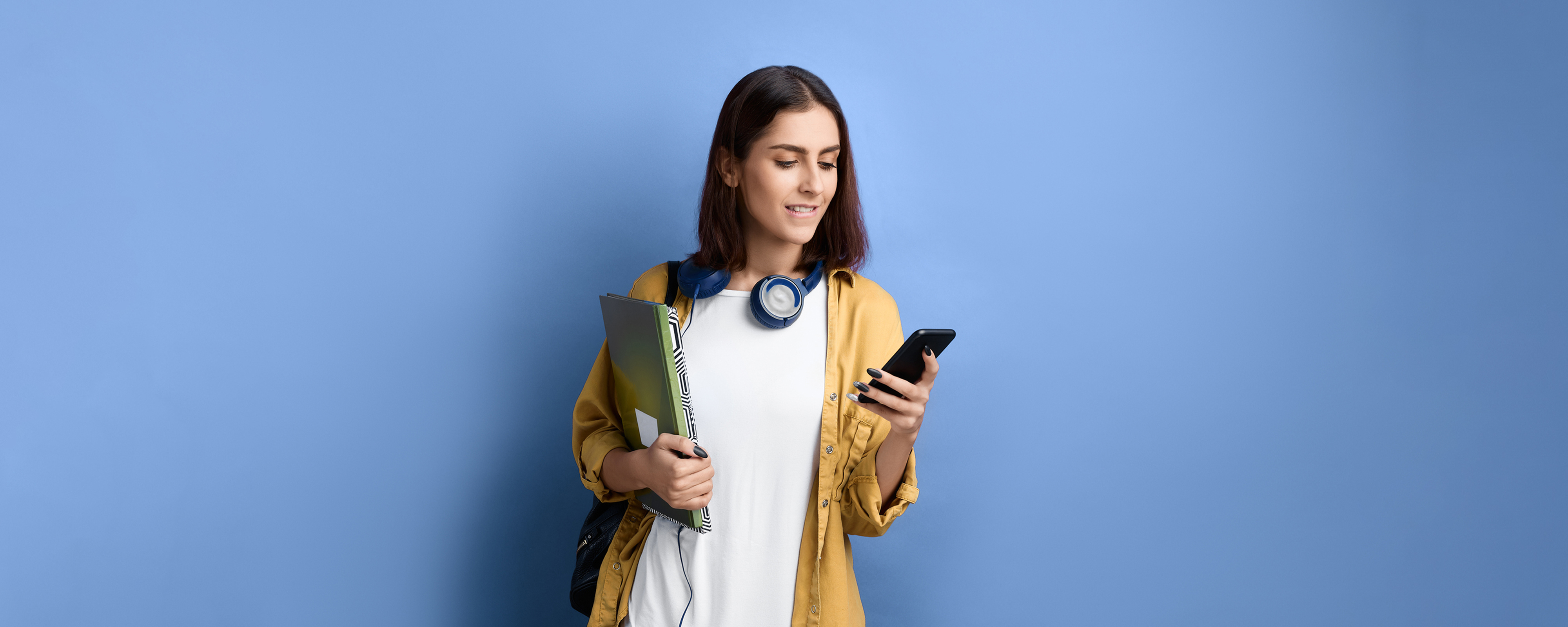 Image of a person standing looking at a phone on a blue background